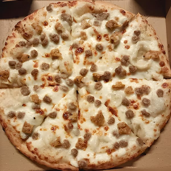 A white pizza with sausage and cheese, sliced and ready to eat in a cardboard box.