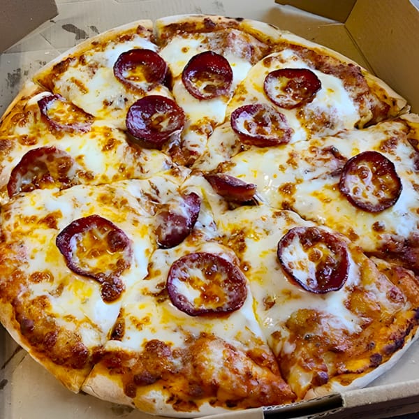 A close-up of a freshly baked pepperoni pizza with melted cheese in a cardboard box.