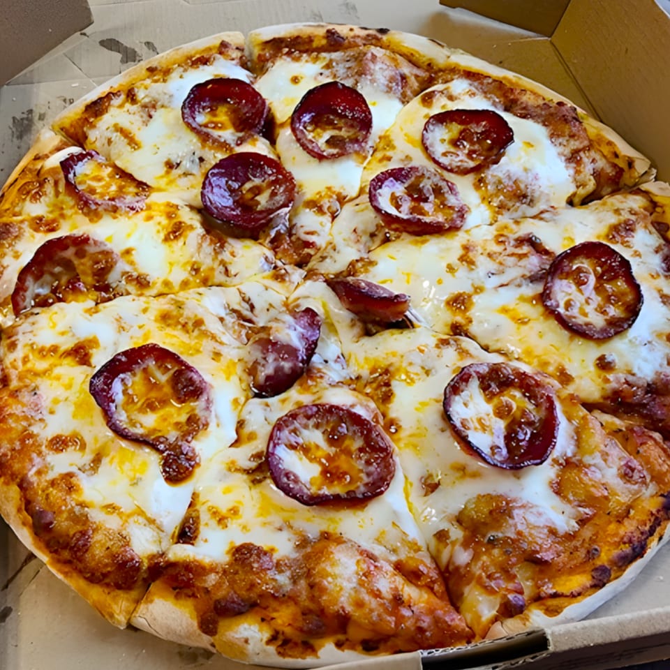 A close-up of a freshly baked pepperoni pizza with melted cheese in a cardboard box.